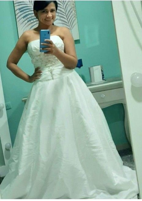 Mujer con vestido de novia blanco sin tirantes tomándose una selfie en el espejo.