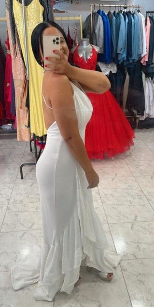Mujer con vestido blanco sin espalda posa en una tienda de vestidos.