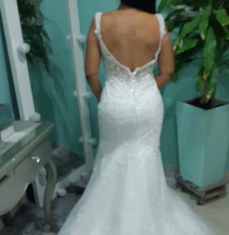 Mujer con vestido de novia blanco con la espalda descubierta, de pie en el interior.