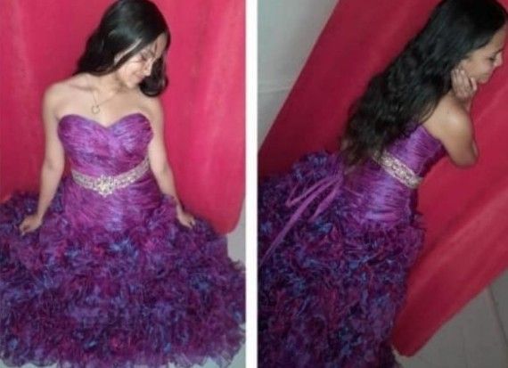 Mujer con un vestido morado sin tirantes y con volantes, posando delante de una cortina roja.