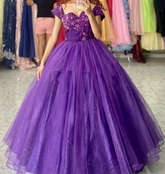 Mujer con un vestido de gala morado brillante con escote corazón posando en una tienda.