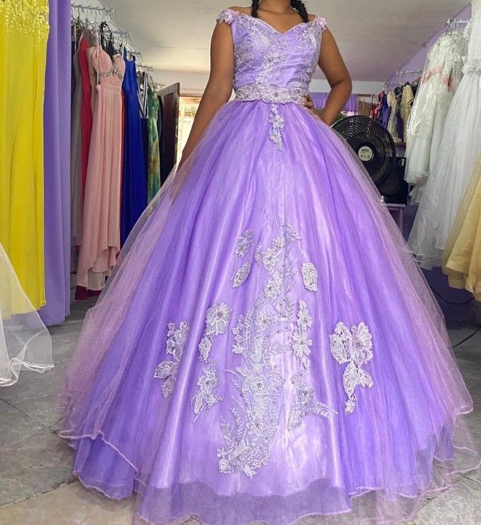 Mujer con un vestido de baile color lavanda con corpiño bordado, de pie en el interior.
