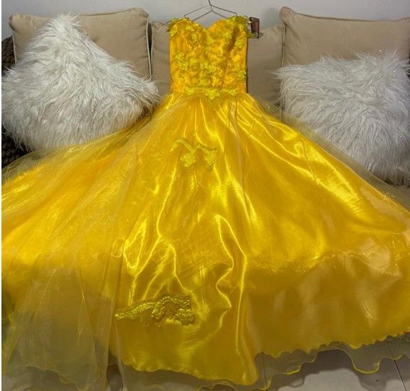 Vestido de gala amarillo con escote corazón, expuesto en una percha.
