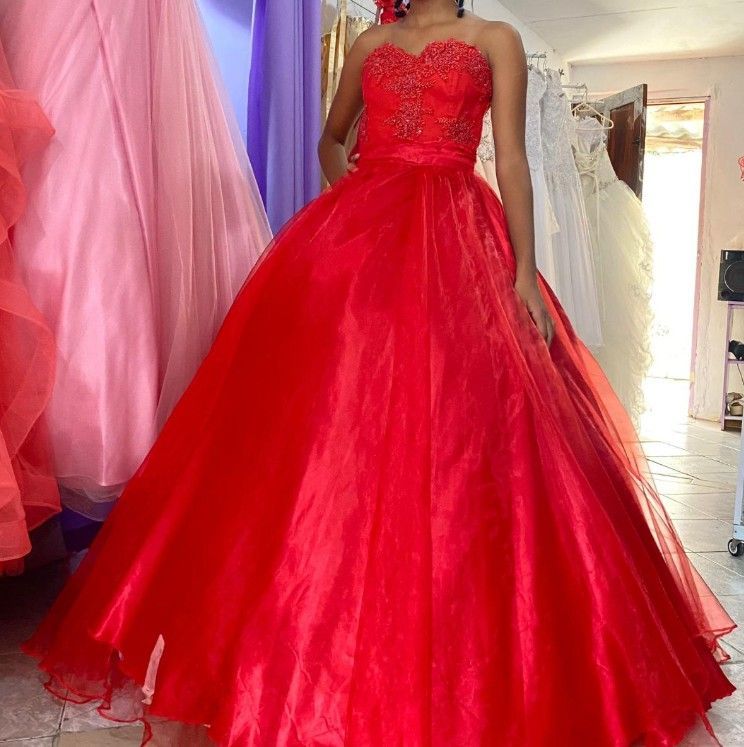 Mujer con un vestido de gala rojo en una tienda de vestidos.