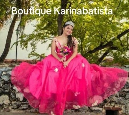 Una mujer con vestido rosa y tiara está sentada afuera.
