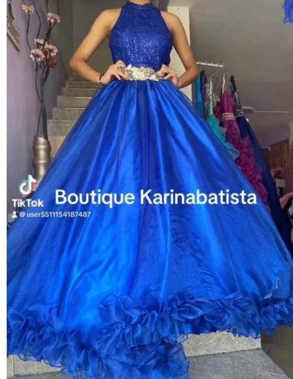 Mujer con un vestido de gala azul brillante con corpiño de cuentas y dobladillo con volantes, en una tienda.