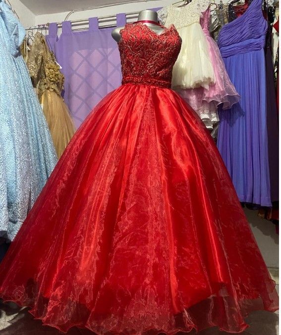Vestido de gala rojo con corpiño bordado y falda amplia, expuesto en una tienda de vestidos.