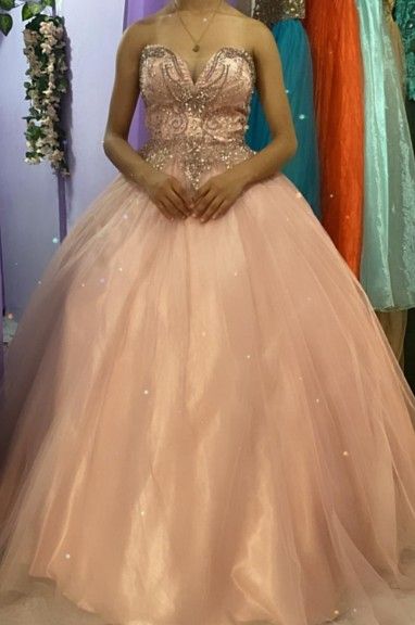 Persona que lleva un vestido de gala palabra de honor de color rosa pálido con un corpiño muy adornado.