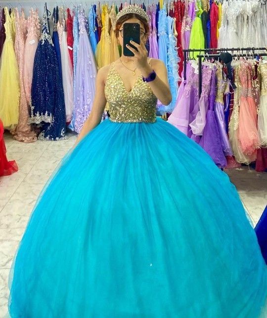 Mujer con un vestido de gala turquesa con corpiño de lentejuelas doradas en una tienda de vestidos.