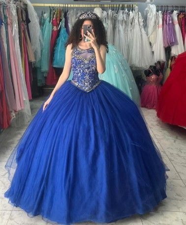 Mujer con un vestido de gala azul real con corpiño enjoyado, sosteniendo un teléfono en una tienda de vestidos.
