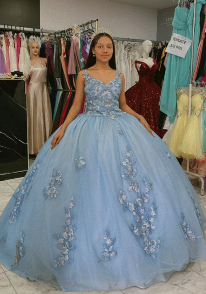 Mujer con un vestido de gala azul claro con adornos florales en una tienda de vestidos.