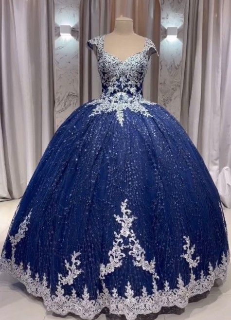 Vestido de gala azul marino con detalles de encaje blanco, exhibido en un maniquí.