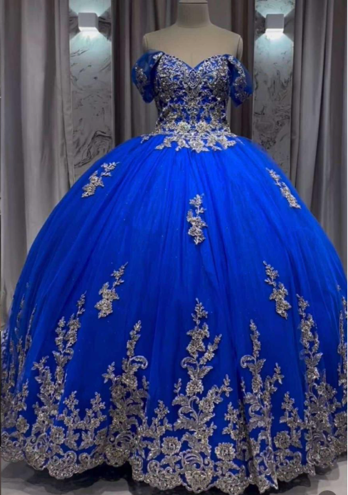 Vestido de gala azul real con bordados plateados y escote que deja los hombros al descubierto.