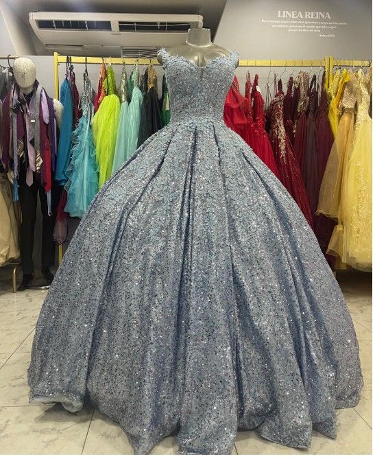 Vestido de gala plateado azulado brillante sobre un maniquí, exhibido en una tienda de vestidos