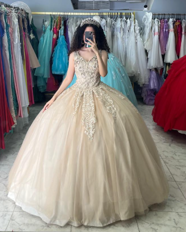 Mujer con un vestido de gala color champán y una tiara, tomándose una selfie en una tienda de vestidos.