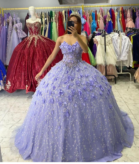 Mujer con un vestido de gala color lavanda con detalles florales, posando en una tienda de vestidos.