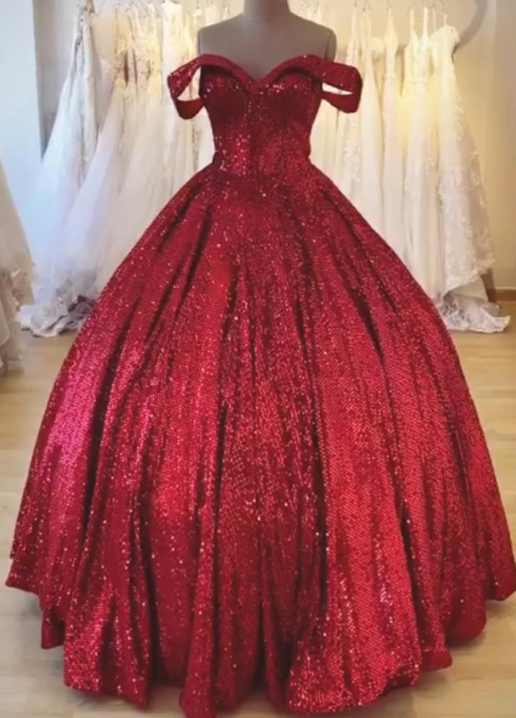 Vestido de gala rojo con lentejuelas, hombros descubiertos, falda amplia y escote corazón, exhibido en una tienda nupcial.