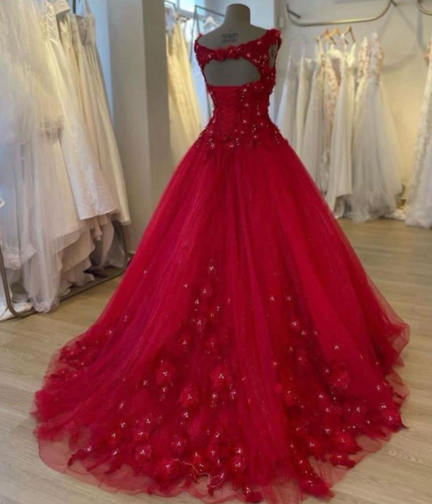 Vestido de gala rojo con adornos florales y una larga cola, expuesto en una tienda de novias.