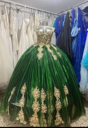 Vestido de quinceañera verde y dorado sobre un maniquí en una tienda de vestidos.