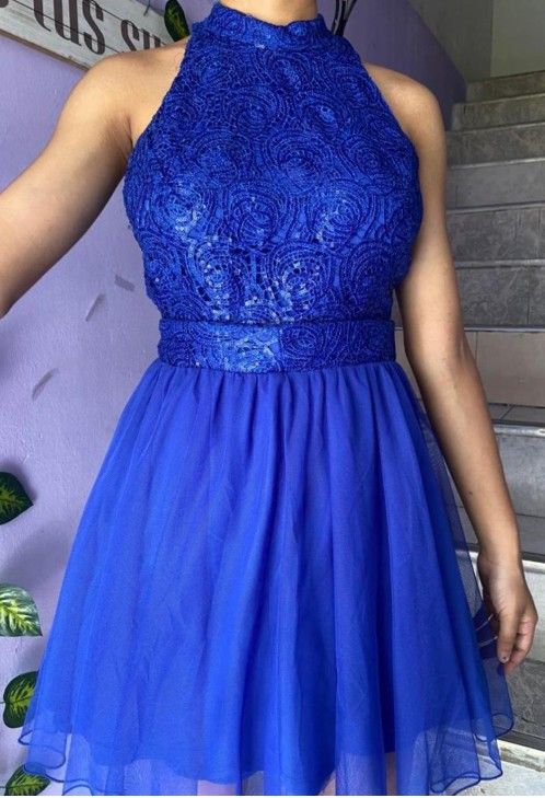 Mujer que lleva un vestido azul de cuello halter con corpiño ajustado y falda acampanada.