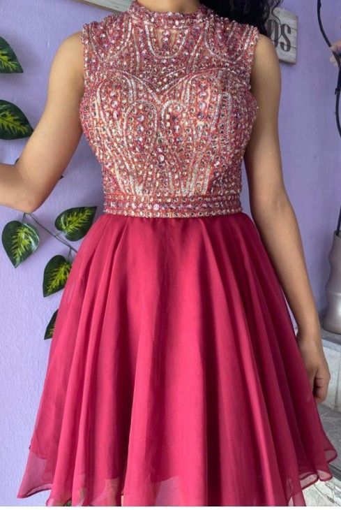 Una persona que lleva un vestido corto y formal con un corpiño con cuentas y una falda acampanada de color burdeos.