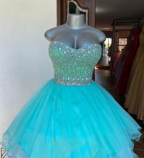 Un vestido turquesa sin tirantes sobre un maniquí; el corpiño está adornado con lentejuelas, falda de tul amplia.