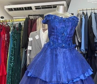 Vestido de gala azul marino sobre un maniquí en una tienda de ropa. Vestidos y trajes al fondo.