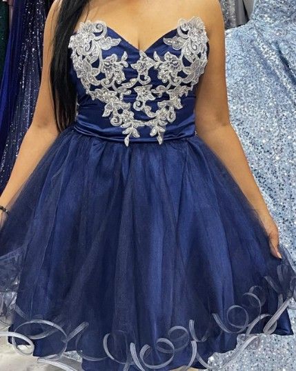 Vestido de fiesta azul marino sin tirantes con corpiño de encaje plateado y falda de tul; usado por una persona.