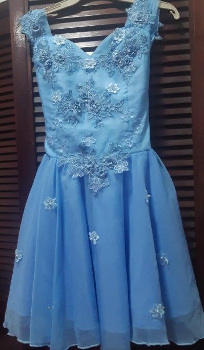 Vestido azul claro con adornos florales colgado en una percha.