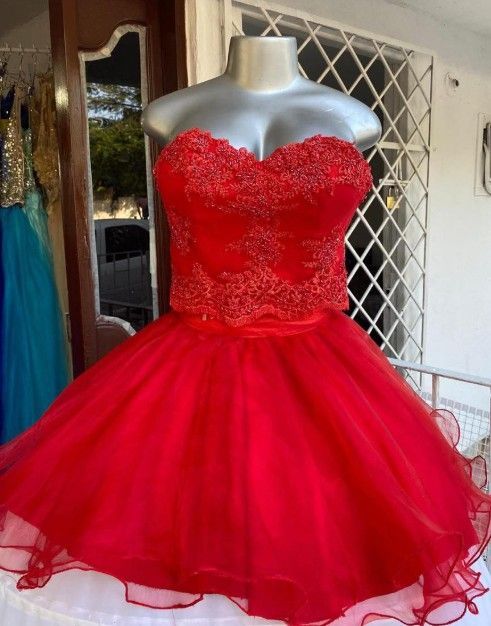 Vestido rojo sin tirantes sobre un maniquí, con corpiño de cuentas y falda de tul.