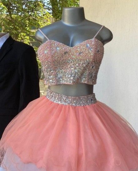 Vestido de gala de dos piezas color melocotón sobre un maniquí; corpiño con joyas, falda de tul, junto a él, una chaqueta
