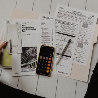 Papers, calculator, and pen on a desk, possibly related to taxes or finance.