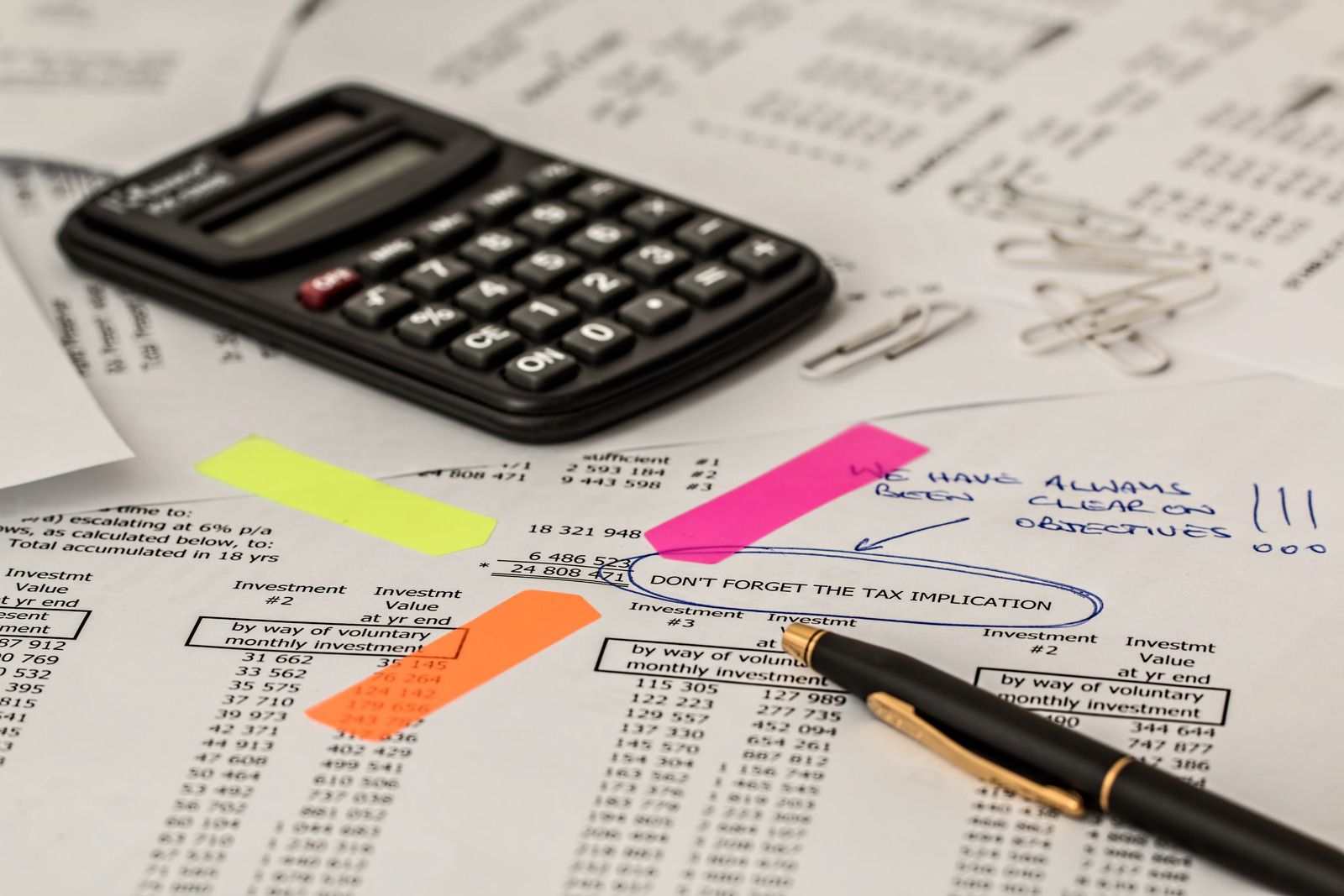 A pen is sitting on a piece of paper next to a calculator