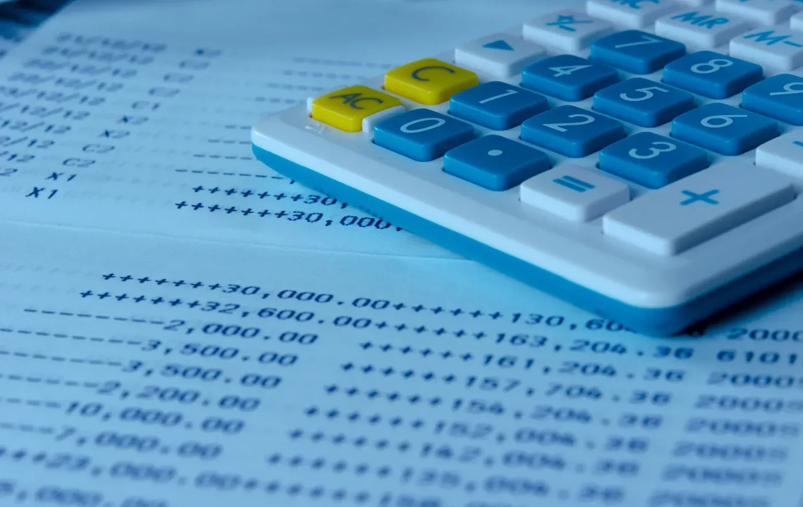 Calculator on top of a ledger with financial data.