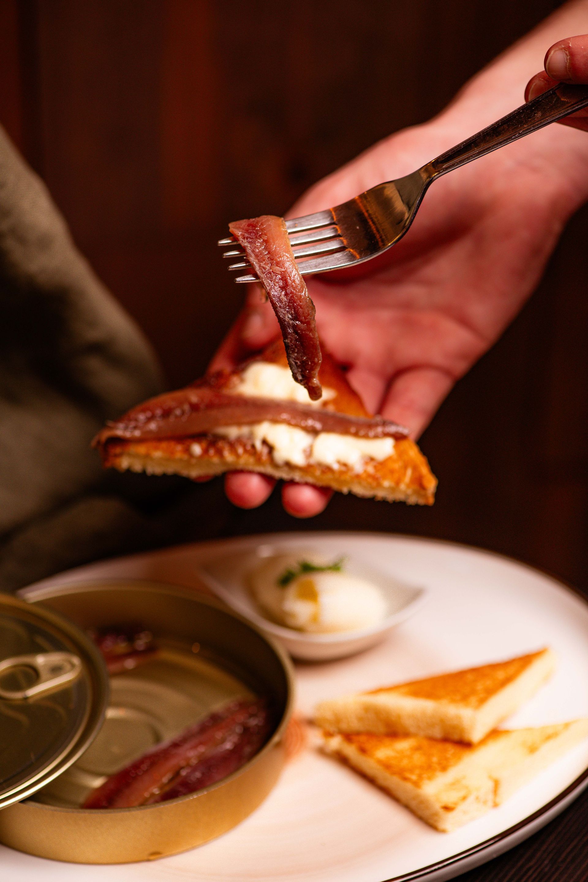 Una persona tiene una forchetta sopra un pezzo di cibo.