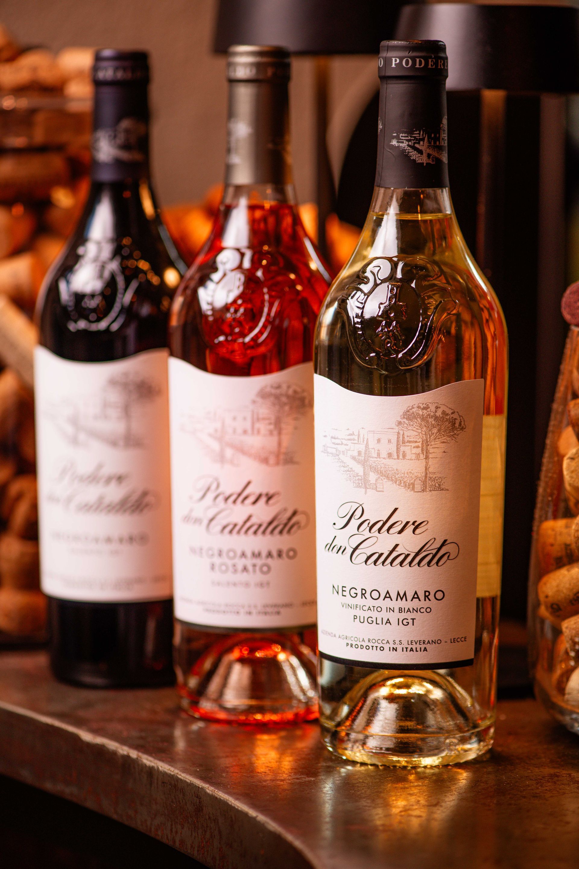 Tre bottiglie di vino sono appoggiate su un tavolo.