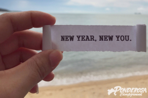 A person is holding a piece of paper that says new year new you