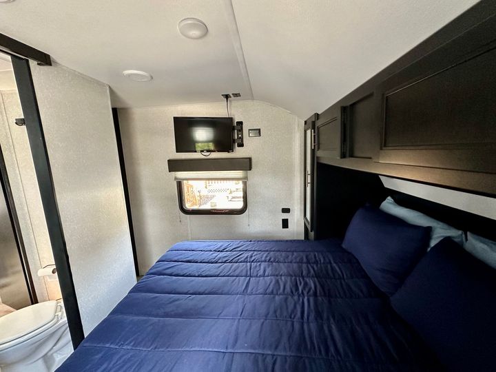 A bedroom with a blue bed and a television above it
