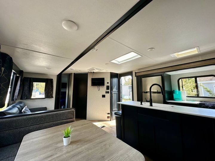 A living room with a table , couch , and kitchen in a rv.