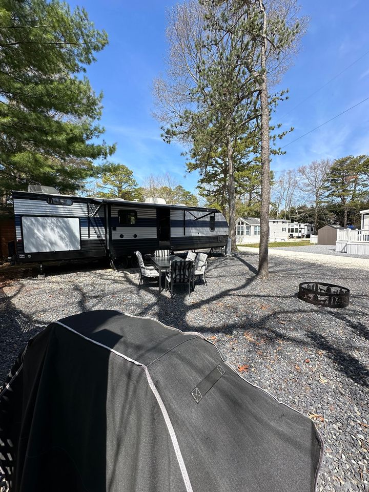A rv is parked in a gravel lot next to a tent.