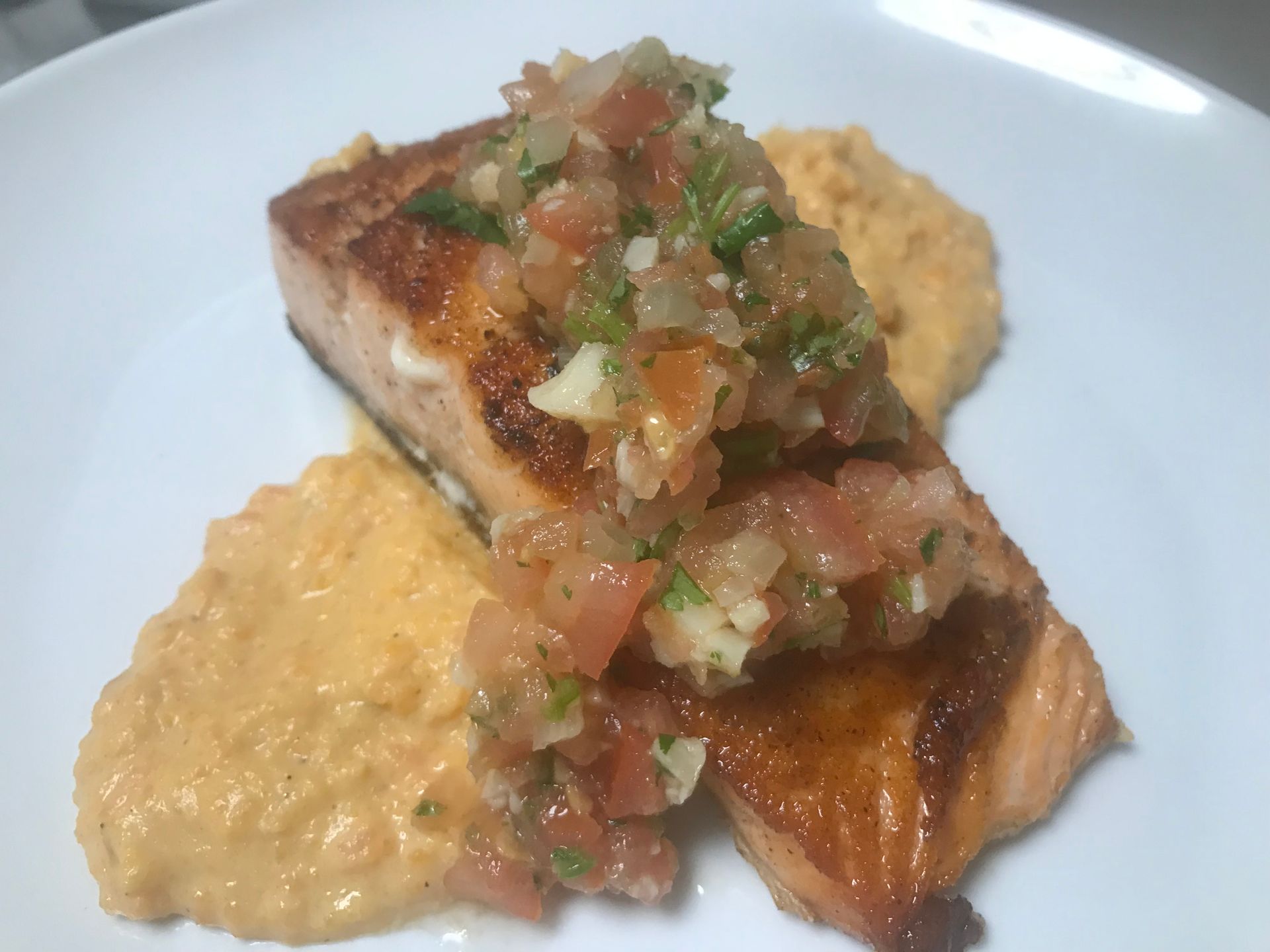 A white plate topped with a piece of salmon and mashed potatoes