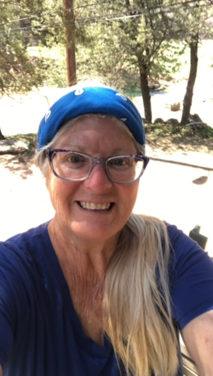 A woman wearing glasses and a blue hat is taking a selfie.