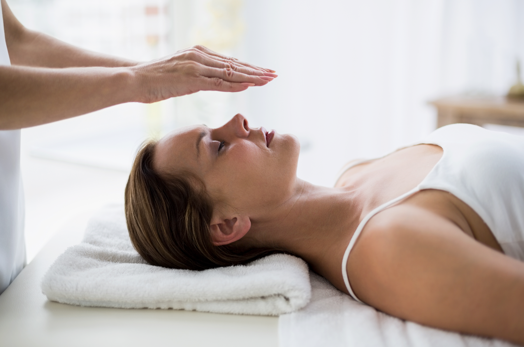 A woman is laying on a bed getting a healing treatment.