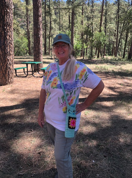 A woman in a floral shirt is standing in the woods