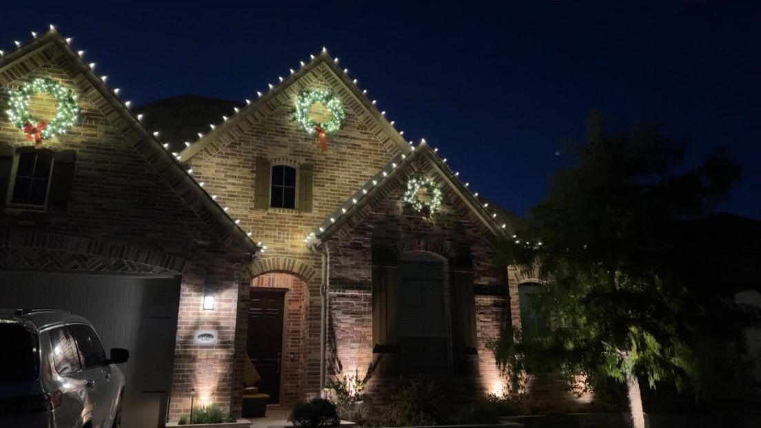 House with Christmas lights and wreaths, lit up at night.