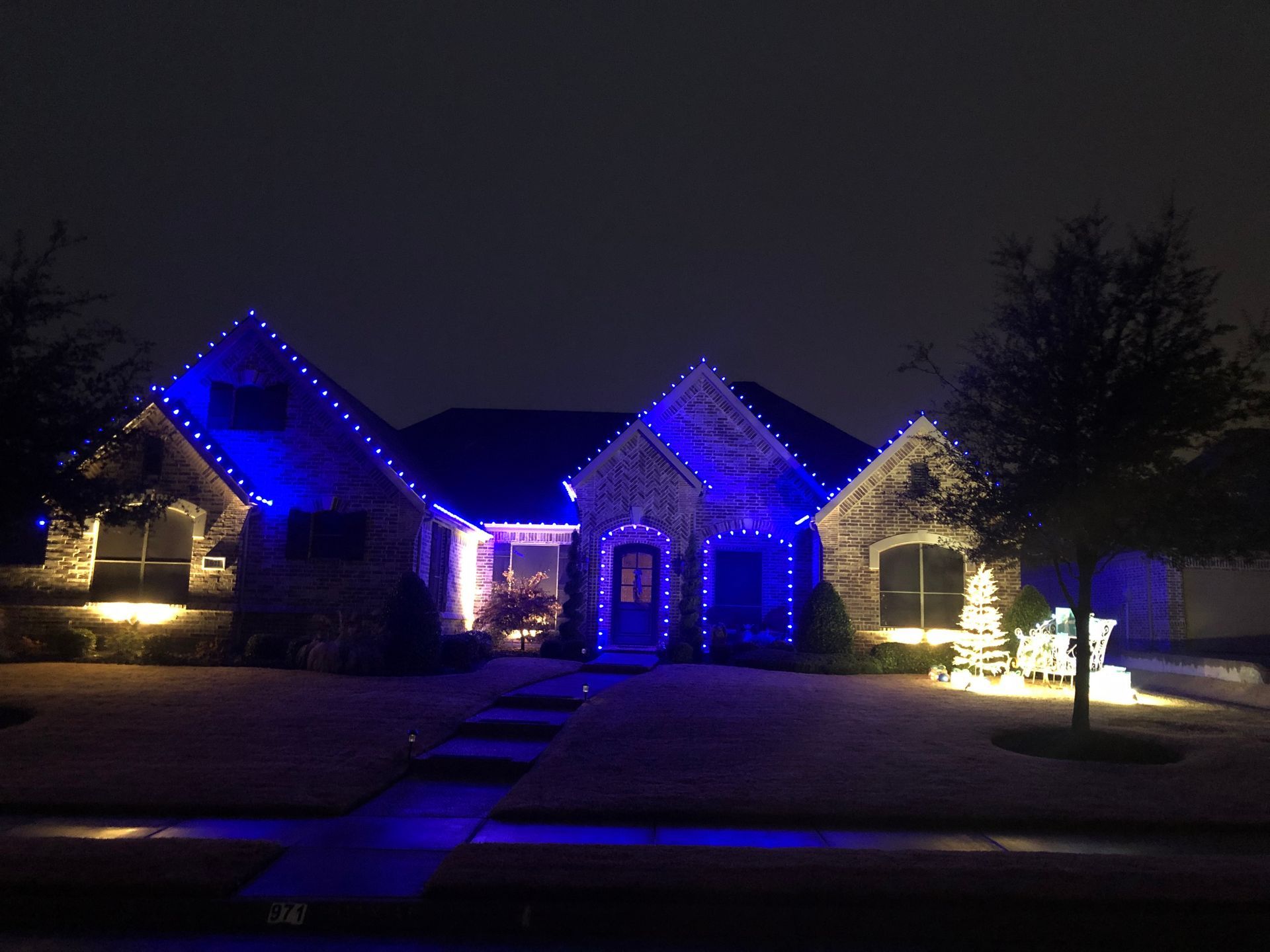 House decorated with blue Christmas lights at night.