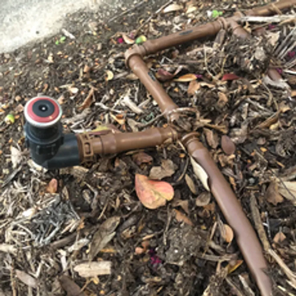 A pipe with a red cap is laying on the ground