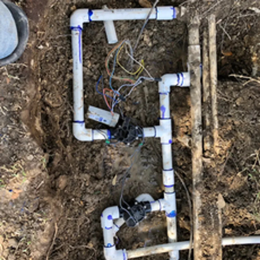 A bunch of pipes are laying in the dirt.