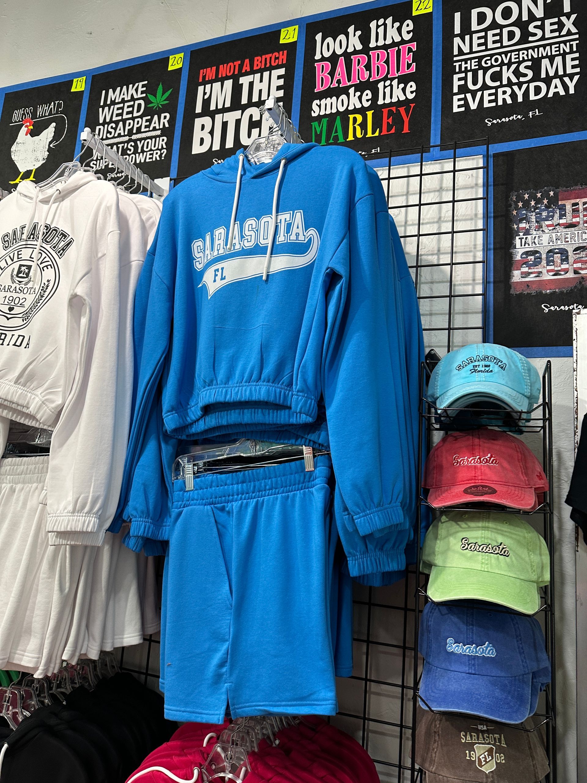 Clothing display with blue sweatsuit and hats; posters with text: 