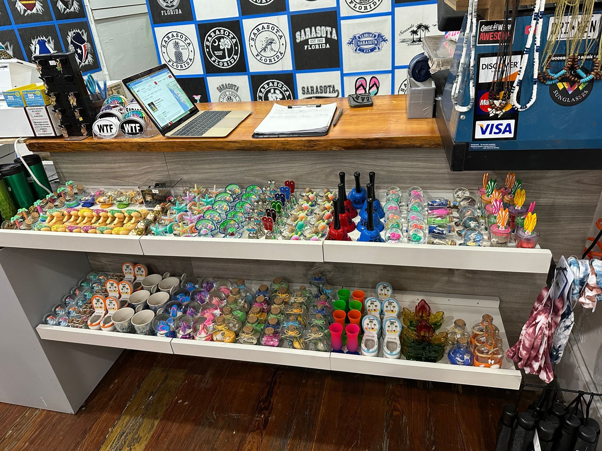 Souvenir shop counter displaying various trinkets and a laptop with a Visa sign.